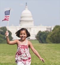 USA, Washington DC, girl (10-11) with US flag running in front of Capitol Building. Photo : Chris