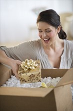 Young woman opening box with gift.