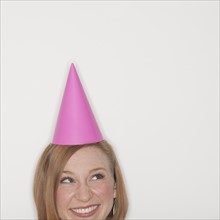 Studio shot of woman wearing pink party hat.