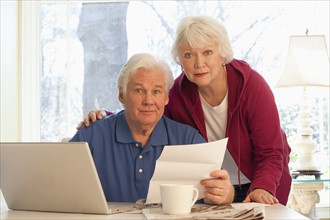 USA, Virginia, Richmond, portrait of senior couple paying bills with laptop. Photo : Mark Edward
