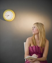 Young woman in evening wear looking at clock. Photo: Jamie Grill Photography