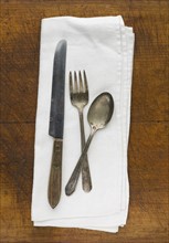 Close up of silver forks, knife and spoon on napkin.