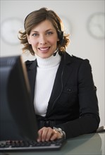 Portrait of smiling woman with headset in customer service office.