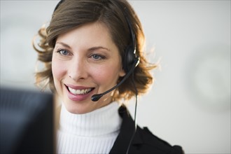 Portrait of smiling woman with headset in customer service office.