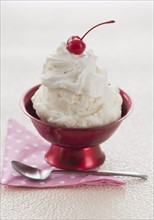 Close up of ice cream with cherry on top.