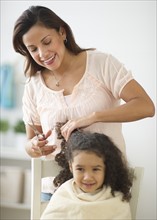 Mother cutting daughter's (6-7) hair.