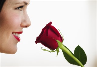 Studio shot of woman smelling red rose.