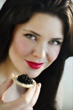 Portrait of young woman eating caviar snack.