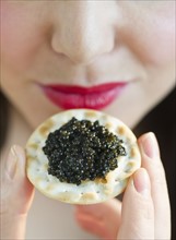 Young woman eating caviar snack, close-up of lips.
