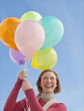 Woman holding bunch of balloons.