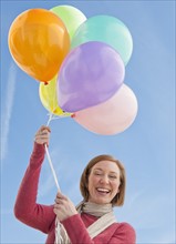 Woman holding bunch of balloons.