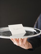 Hand holding tray with envelope. Photo : Jamie Grill Photography