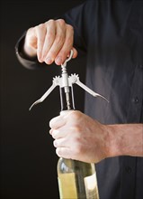 Man opening wine bottle, close-up of hands. Photo : Jamie Grill Photography