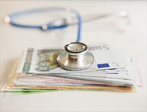 Studio shot of stethoscope on banknotes. Photo : Jamie Grill Photography