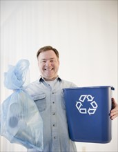 Man holding bag and recycling bin. Photo: Jamie Grill Photography