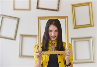 Portrait of woman holding picture frame over face. Photo: Daniel Grill