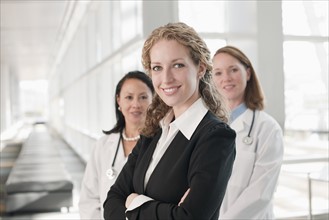 Portrait of businesswoman with doctors in background. Photo: Mark Edward Atkinson