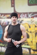 USA, Washington, Seattle, man in workout wear in front of graffiti wall. Photo: Take A Pix Media