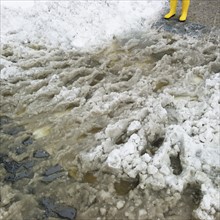 USA, New York, New York City, close up of feet in yellow rubber boots in slush.