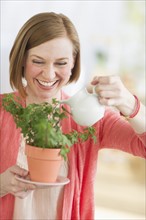 Woman watering potted plant.