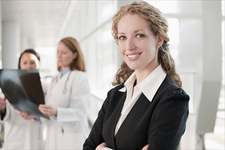 Portrait of businesswoman with doctors in background. Photo: Mark Edward Atkinson