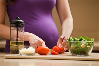 Young pregnant woman preparing food. Photo: Mike Kemp