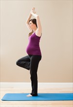 Young pregnant woman exercising, standing on one leg. Photo : Mike Kemp