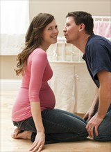 Young pregnant woman about to be kissed by mid adult man. Photo : Mike Kemp