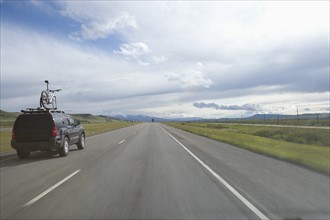 USA, Montana, Car driving down rural highway. Photo : Noah Clayton