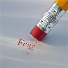 Studio shot of pencil erasing the word fear from piece of paper. Photo : Daniel Grill