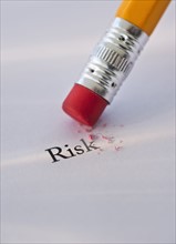 Studio shot of pencil erasing the word risk from piece of paper. Photo: Daniel Grill