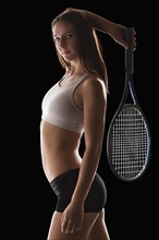 Studio portrait of young woman holding tennis racquet. Photo : Mike Kemp