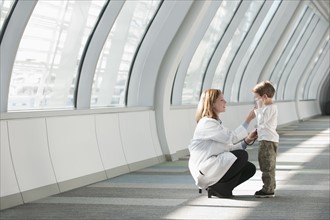 Female doctor talking to boy (6-7) in corridor. Photo : Mark Edward Atkinson
