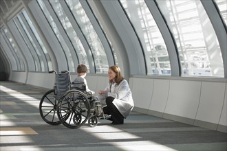 Female doctor talking to boy (6-7) in wheelchair. Photo: Mark Edward Atkinson