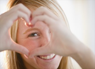 Woman making heart shape with fingers. Photo: Jamie Grill Photography