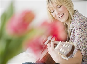 Young woman playing guitar. Photo : Jamie Grill Photography