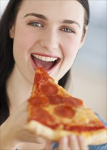 Portrait of smiling young woman eating pizza.