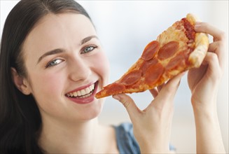 Portrait of smiling young woman eating pizza.