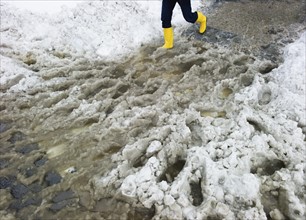 USA, New York, New York City, legs of person in yellow rubber boots walking in slush.