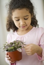Portrait of girl (6-7) holding potted plant.