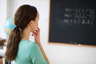 Teenage girl (14-15) looking at blackboard.