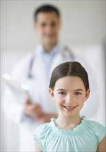 Portrait of girl (8-9), with doctor behind.