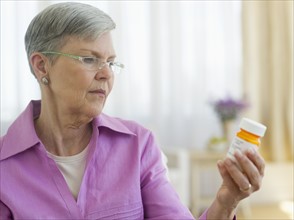 Senior woman looking at pill bottle.