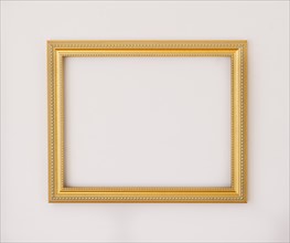 Studio shot of golden picture frame on white background. Photo : Daniel Grill