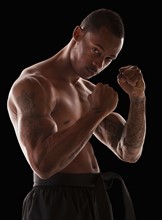 Studio portrait of muscular man in fighting stance. Photo : Mike Kemp