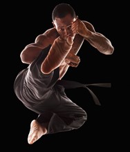 Studio shot of martial arts practitioner in mid-air kick. Photo : Mike Kemp