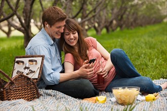 USA, Utah, Provo, Young couple with mp3 player in orchard. Photo : Mike Kemp