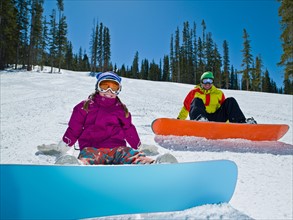 USA, Colorado, Telluride, Father and daughter (10-11) posing with snowboards in winter scenery.