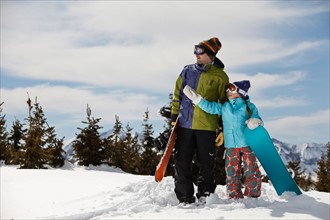 USA, Colorado, Telluride, Father and daughter (10-11) standing with snowboards in winter scenery.