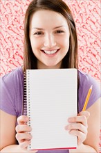 Portrait of smiling young woman holding blank notebook. Photo : Jamie Grill Photography